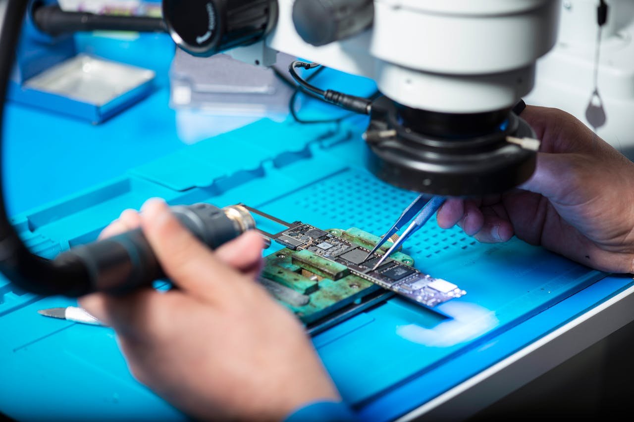 services-01 Close-up of technician repairing electronic circuit board under a microscope in Toronto lab.
